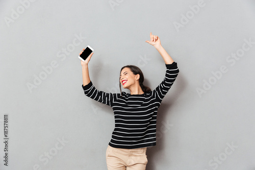 Portrait of a cheerful woman holding mobile phone