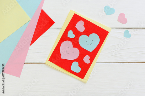 Valentines day or Mothers day greeting card with pink and blue hearts. Scissors, glue stick, colored paper sheets set on a wooden table. Fun art and craft with paper for children. Top view 