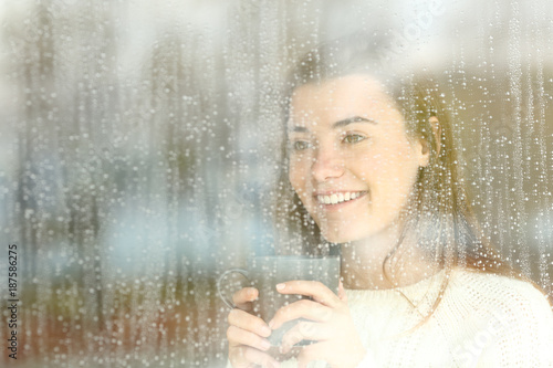 Canvastavla Positive teen looking through a window in a rainy day