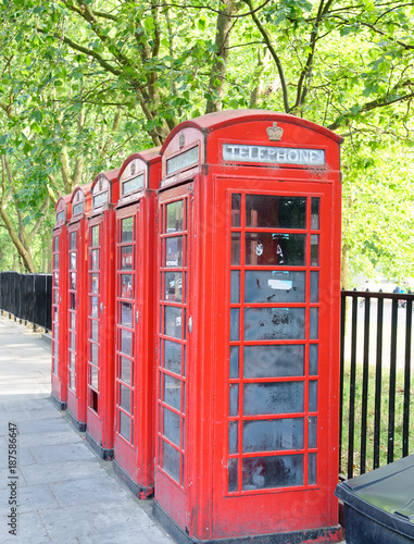 Red public phone booths in London along a city park photo