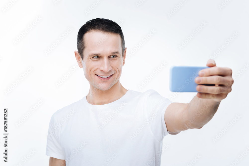 Selfie time. Happy positive delighted man smiling and taking selfie while being in a positive mood Selfie time. Happy positive delighted man smiling and taking selfie while being in a positive mood