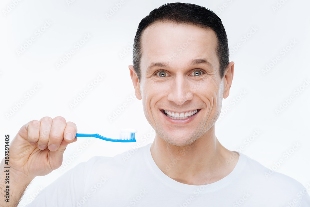 Absolutely healthy teeth. Cheerful nice happy man looking at you and showing his smile while holding a toothbrush Absolutely healthy teeth. Cheerful nice happy man looking at you and showing his smile while holding a toothbrush