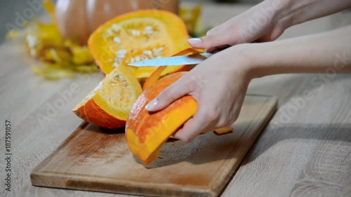 Women's hands peel raw pumpkin from the skin photo