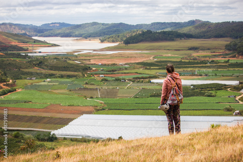 back view of man looking at beautiful landscape with agricultural fields and mountains  vietnam  dalat region