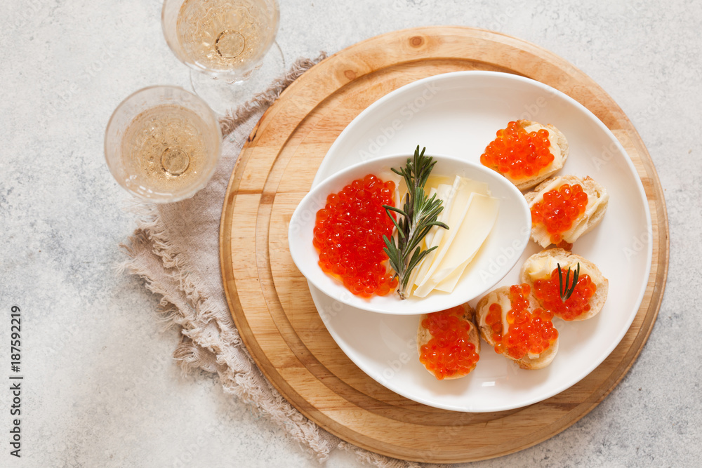 Red caviar on baguette canape and champagne on white background from above Red caviar on baguette canape and champagne on white background from above