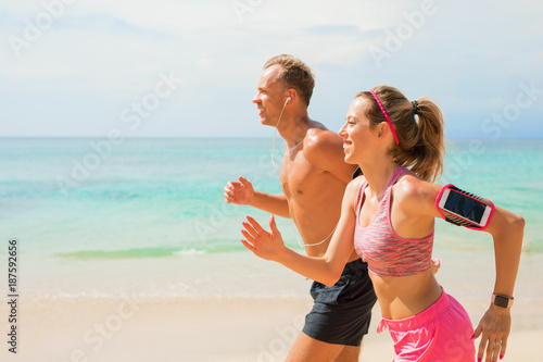 Couple using wearable devices while jogging on the beach