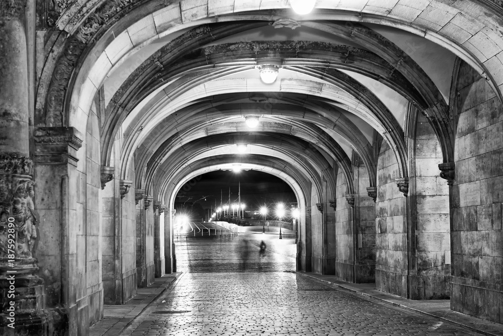 Shadows of people walking at night under ancient medieval loggias