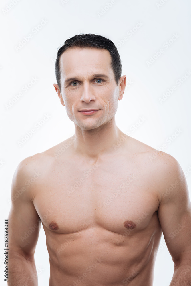 Foto Stock Keeping fit. Handsome nice well built man smiling and looking at  you while keeping fit | Adobe Stock