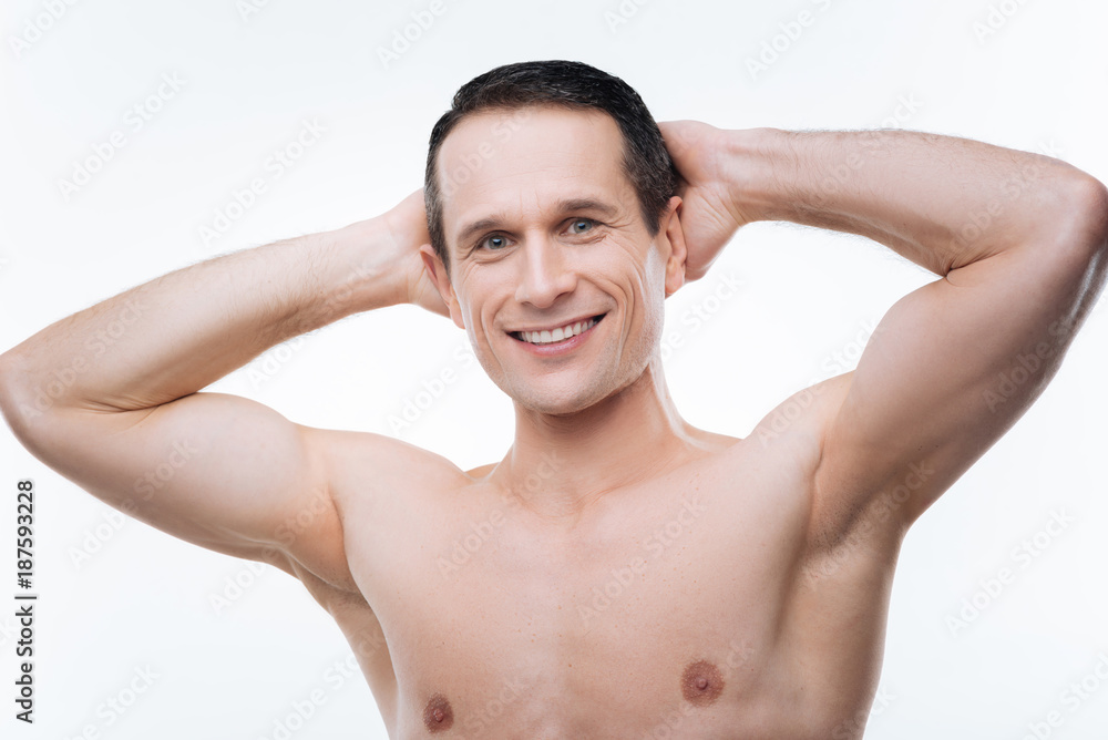 Fototapeta premium I feel comfortable. Happy positive good looking man holding his hands behind his hands and smiling while enjoying his rest