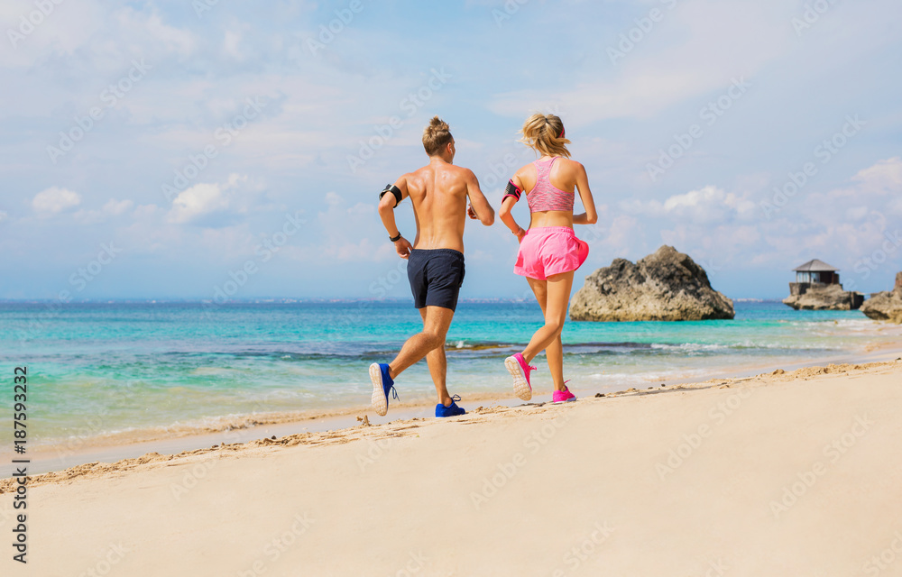 Couple using wearable devices while jogging by the ocean