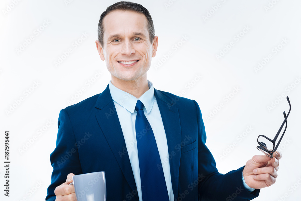 Break from work. Cheerful nice smart businessman looking at you and smiling while having a break from work Break from work. Cheerful nice smart businessman looking at you and smiling while having a break from work