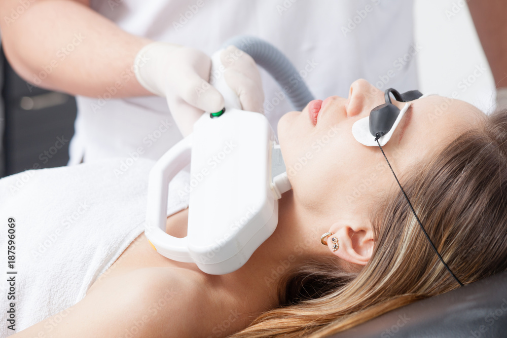 Naklejka premium woman during face laser therapy in cosmetics