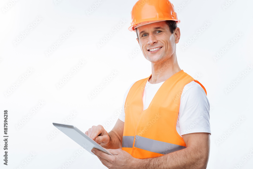Safety equipment. Positive happy nice engineer smiling and toughing his helmet while carrying his draughts Safety equipment. Positive happy nice engineer smiling and toughing his helmet while carrying his draughts