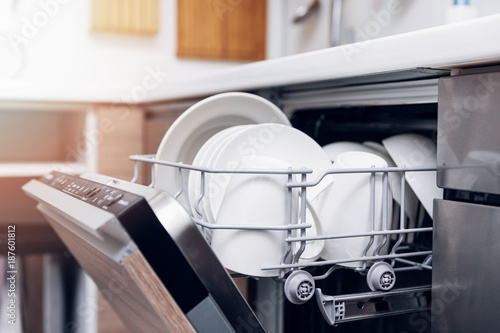 open dishwasher with clean dishes at home kitchen photo