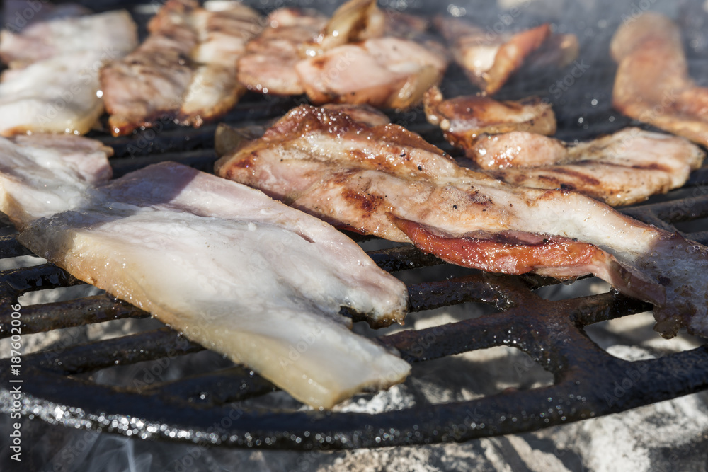 Grilling bacon, pork chop with delicious toasted traces. Smoke. Close up view Grilling bacon, pork chop with delicious toasted traces. Smoke. Close up view