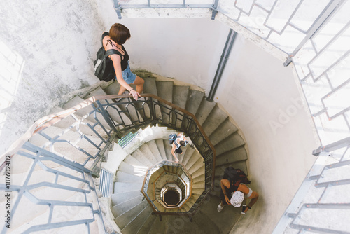High angle view of three young adults moving down spiral staircase, Como, Lombardy, Italy photo