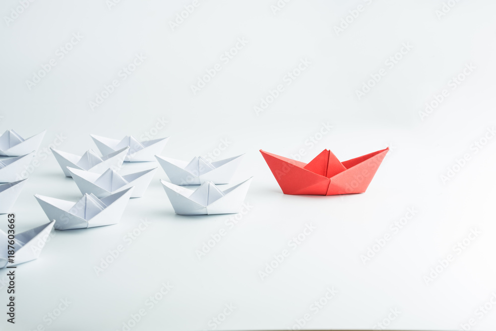 Leadership concept with red paper ship leading among white Leadership concept with red paper ship leading among white