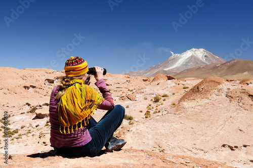 South America - The surreal landscape in the Eduardo Avaroa National Reserve of Andean Fauna near Chilean border. The woman will look through binoculars on the mountain