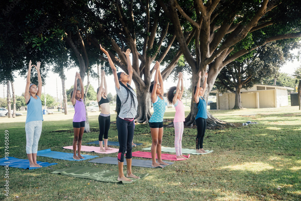 Schoolgirls practicing yoga pose on school sports field Schoolgirls practicing yoga pose on school sports field