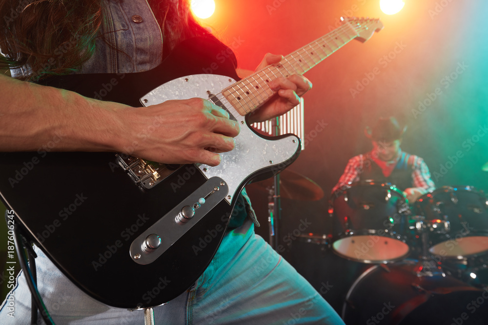 Obraz premium The rock band performs on stage. The guitarist is in the foreground.