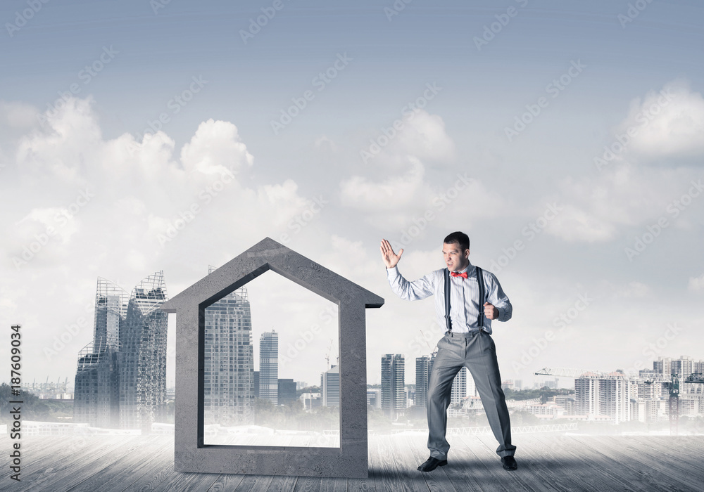 Manager man crashing stone home as symbol for real estate insura Manager man crashing stone home as symbol for real estate insura
