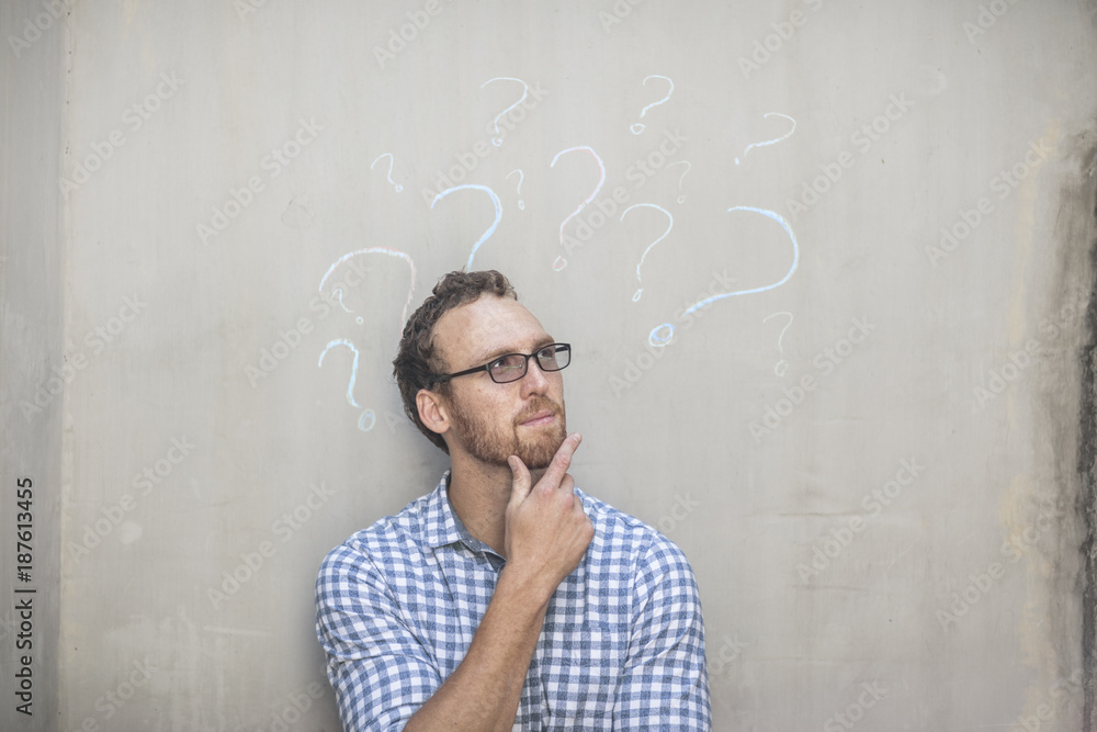 Man standing next to a concrete wall with chalk question mark drawings Man standing next to a concrete wall with chalk question mark drawings