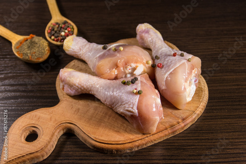 Raw chicken legs with spices on wooden cutting board on a table