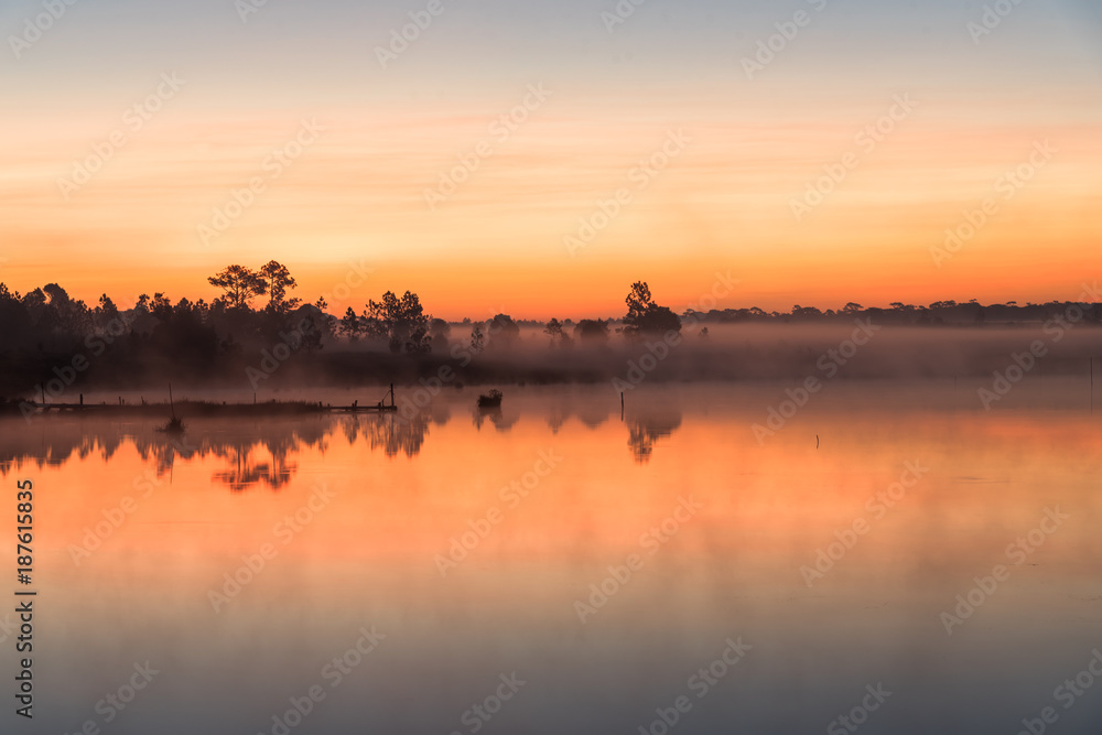 Morning sunrise over the lake with silhouette tree reflect on water surface at Phu Kradaung, national park in Thailand.