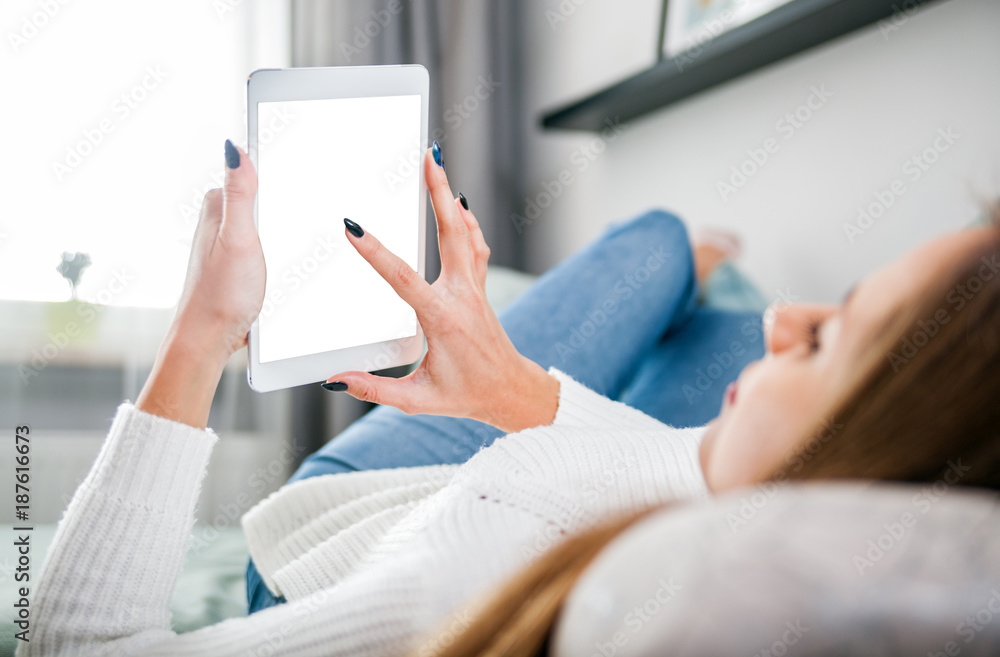 Woman on sofa at home using tablet computer and relaxing Woman on sofa at home using tablet computer and relaxing