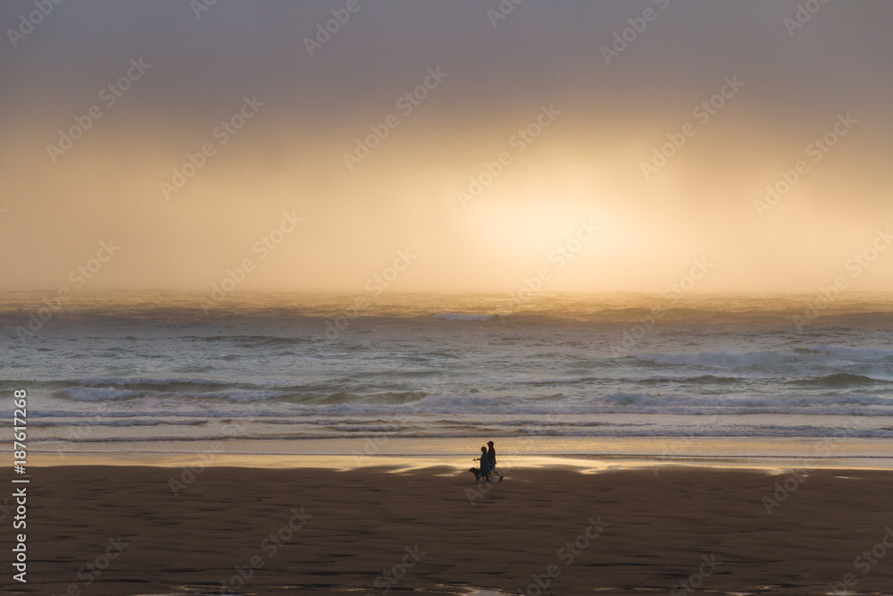 couple with dog during colorful sunset above sand beach in bayocean peninsula park oregon, USA