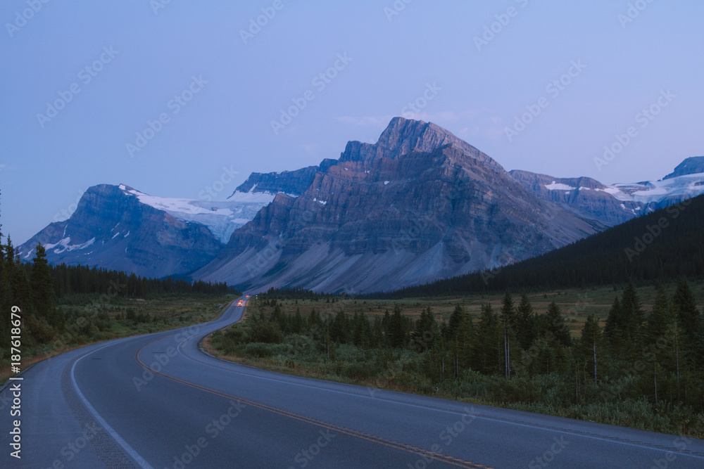 Icefields Parkway after sunset with cars on road in Rocky Mountains, Alberta