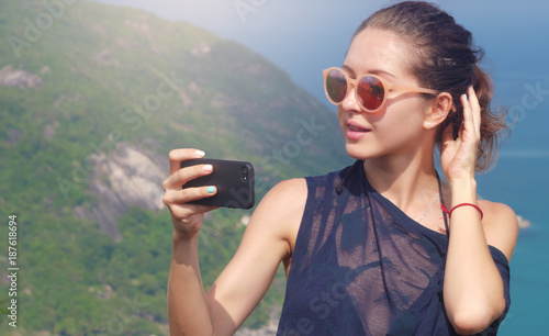 Beautiful girl traveler is taking a selfie with sea view at a height