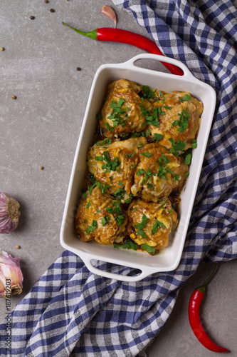 Chicken thighs gratin with sour cream and cheese, parsley, garlic, chilli pepper in the white baking dish.