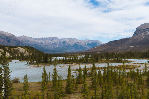 Scenic remote wide valley with river and forest in Rocky Mountains in Canada on cloudy day © Martin Hossa