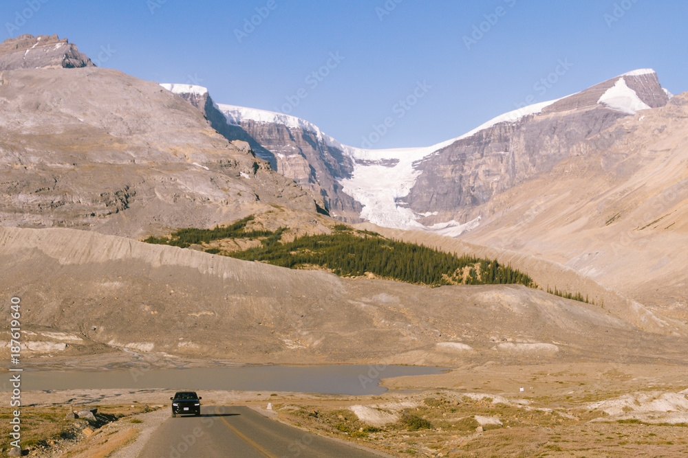Scenic road through glacier field with Athabasca glacier in the background during sunrise