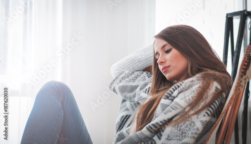 Woman at home sitting on chair and thinking about something