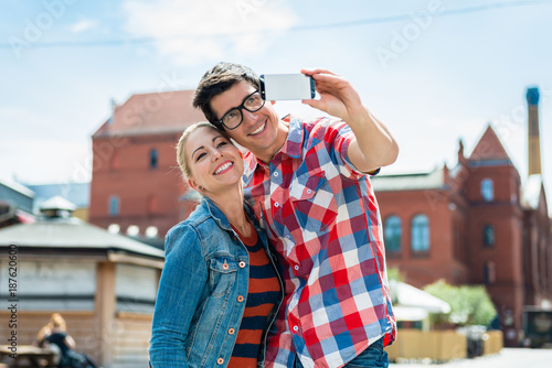 Tourist couple, woman and man, taking holiday selfie on rooftop in Berlin