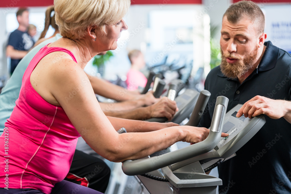 Personal trainer instructs senior woman about spinning at the gym Personal trainer instructs senior woman about spinning at the gym