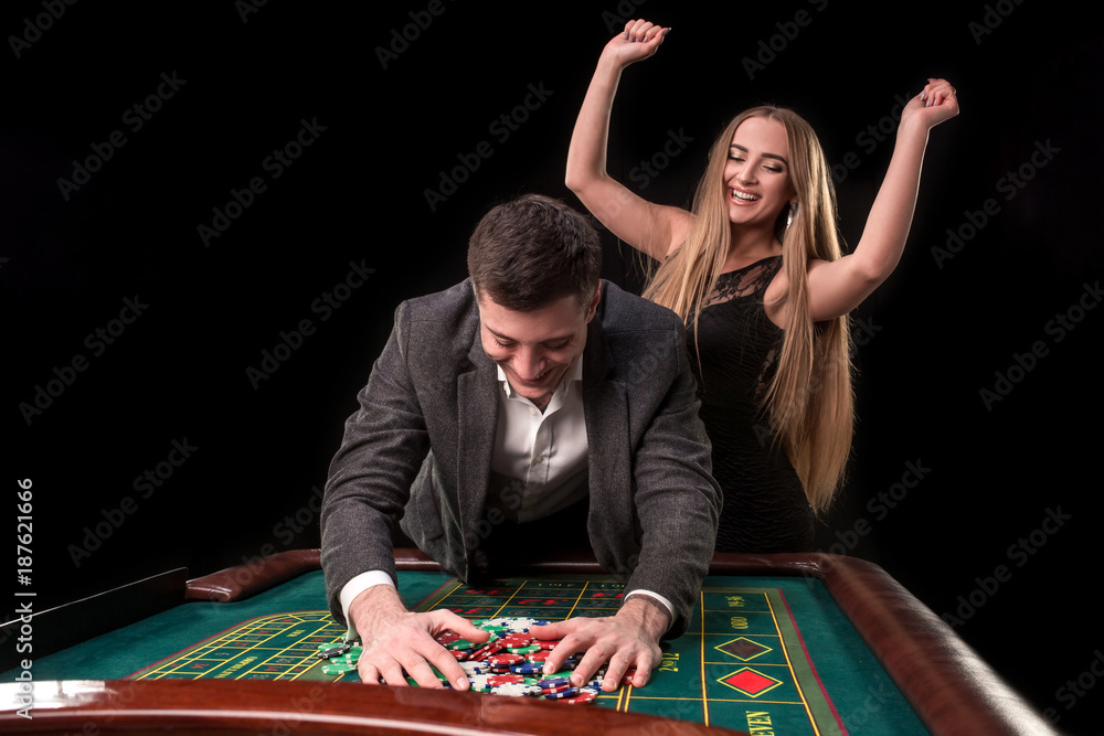 Young beautiful couple takes their winnings at the roulette table at the casino Young beautiful couple takes their winnings at the roulette table at the casino