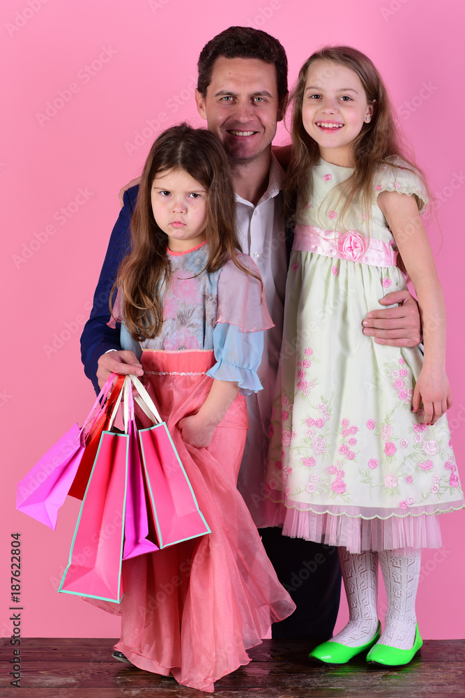 Schoolgirls and father hold pink packets. Girls and man Schoolgirls and father hold pink packets. Girls and man