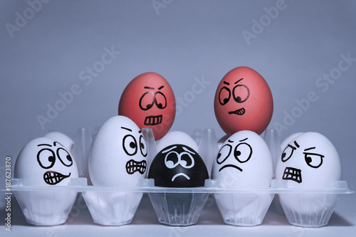 Faces on chicken eggs in the form of facial expressions, reflecting emotions. The concept of racism, misunderstanding, a barrier in relations, denial of society. Barriers between people, prejudice.