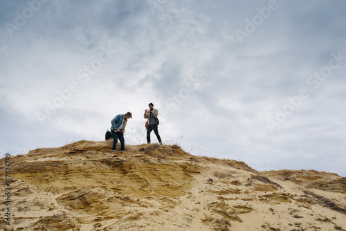 Travelers with backpack on top of dune enjoying view landscape. Traveling among forest and coast of lake, freedom and active lifestyle concept