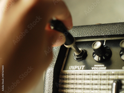 guitar amplifier with hand on cable audio jack photo