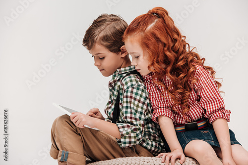 beautiful little child looking at friend using digital tablet isolated on grey