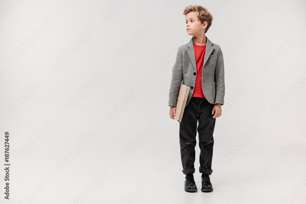 stylish little schoolboy with big book isolated on grey stylish little schoolboy with big book isolated on grey