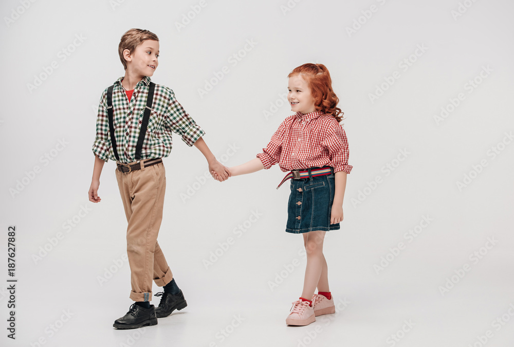 adorable little kids holding hands and walking together isolated on grey adorable little kids holding hands and walking together isolated on grey