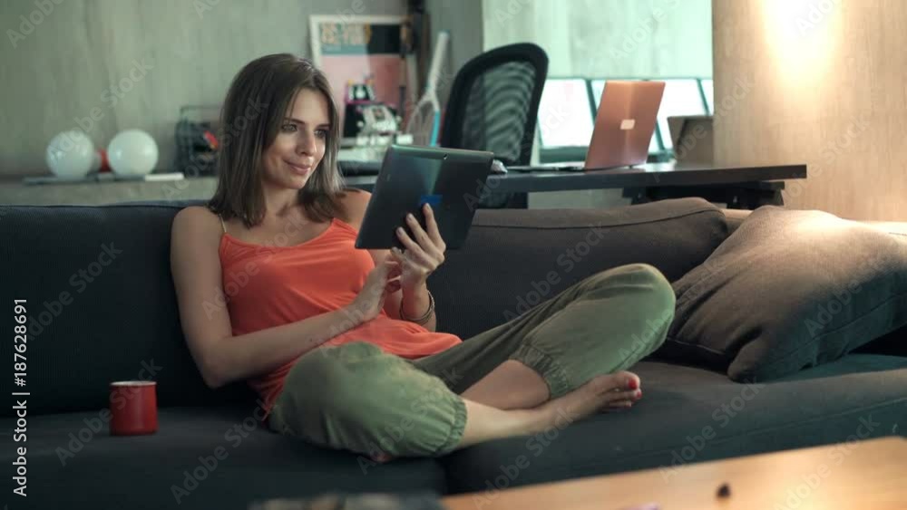 Young woman watching movie on tablet sitting on sofa at home
Young woman watching movie on tablet sitting on sofa at home