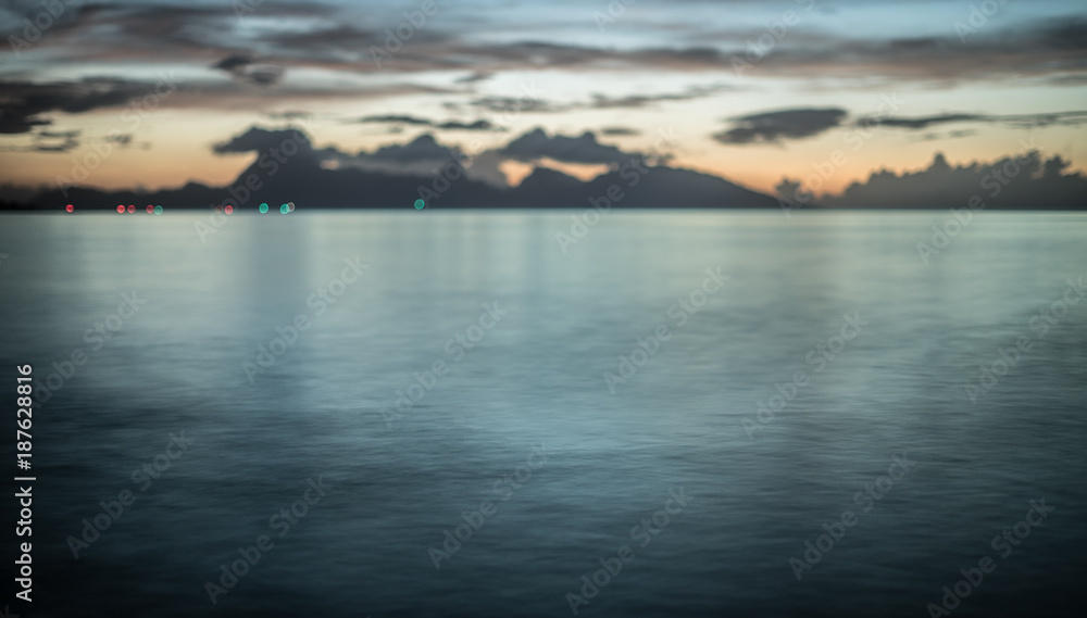 A calm sea during a sunset in front of an island