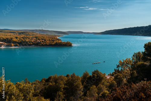 A boat navigates the turquoise blue water of a magnificent lake in Provence