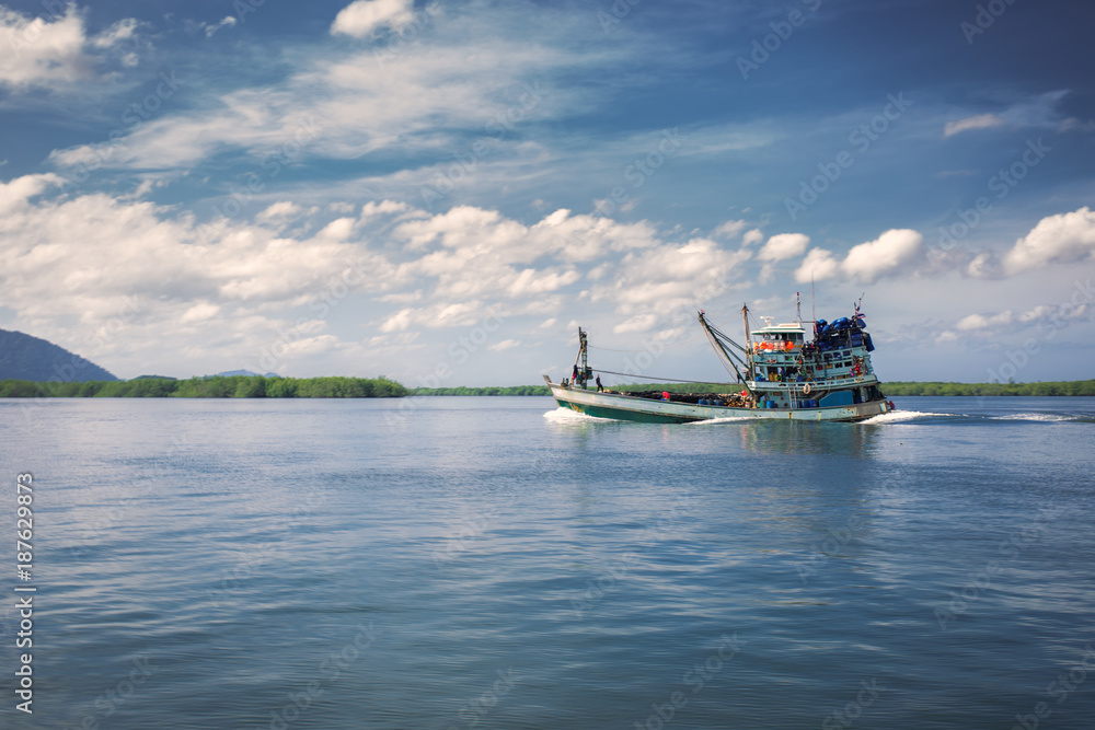 Obraz premium Fishing boat heading out to ocean in the morning.
